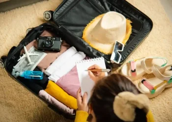 امرأة ترتب حقيبة السفر من قائمة الأشياء الضرورية