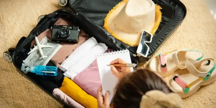 امرأة ترتب حقيبة السفر من قائمة الأشياء الضرورية