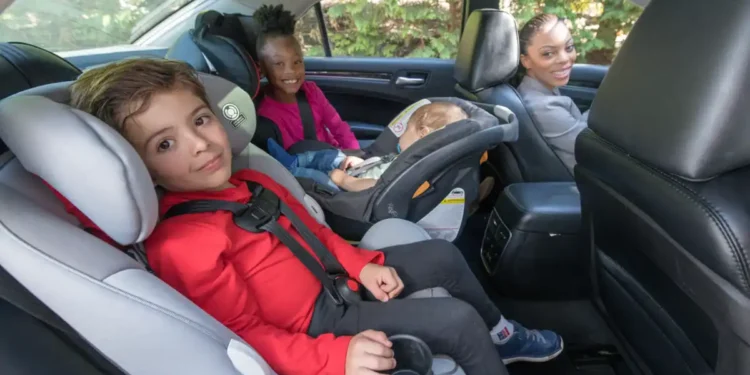 أم تركب السيارة مع أطفالها جالسين في المقعد الخلفي على كرسي السيارة المخصص لهم
